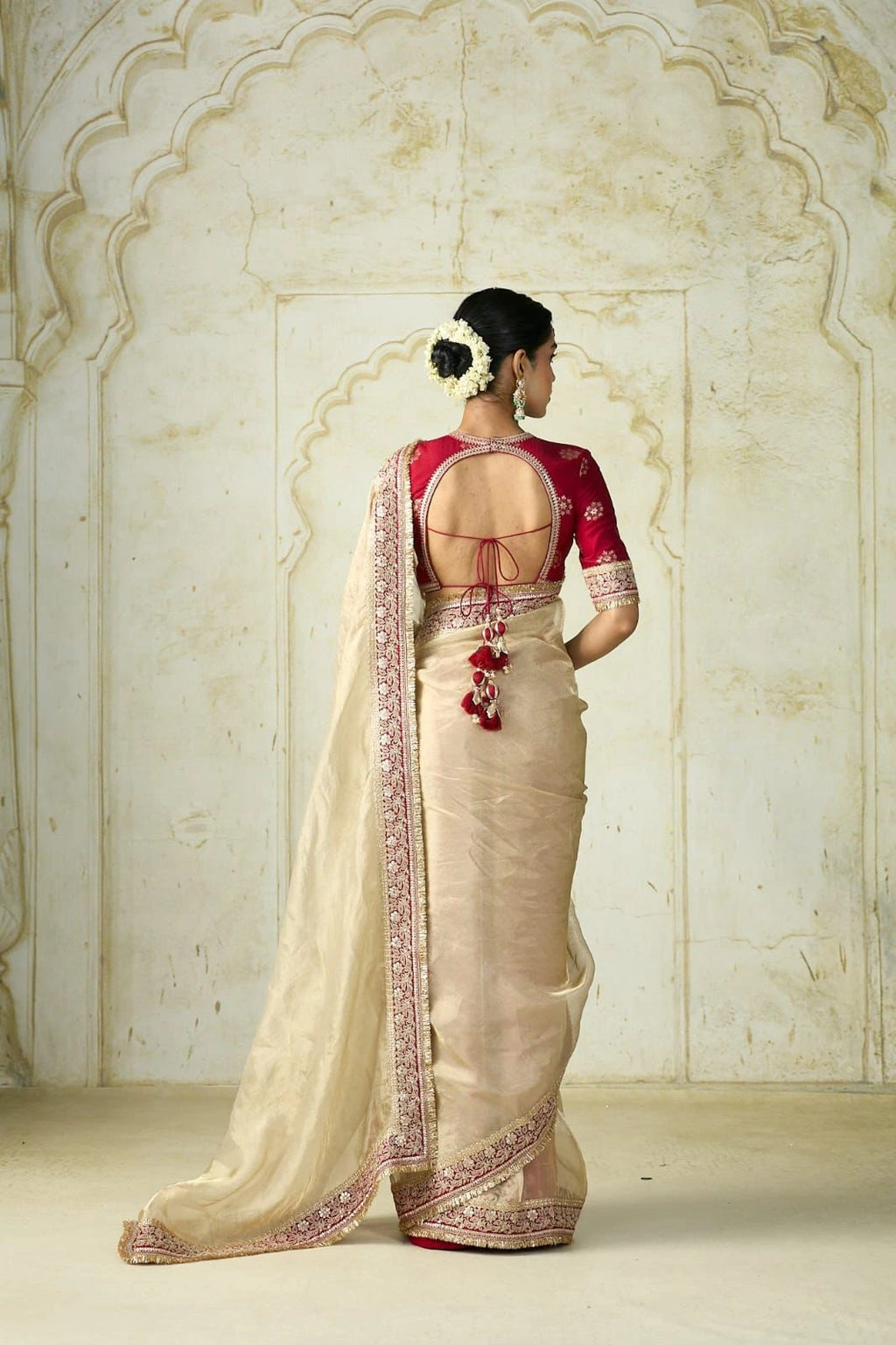 Elegant cream golden saree with embroidered border paired with a red blouse.