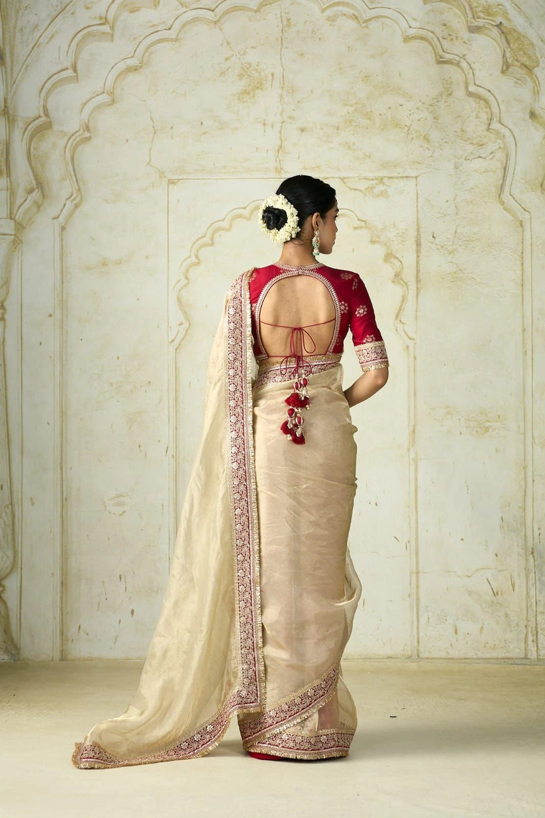 Elegant cream golden saree with embroidered border paired with a red blouse.