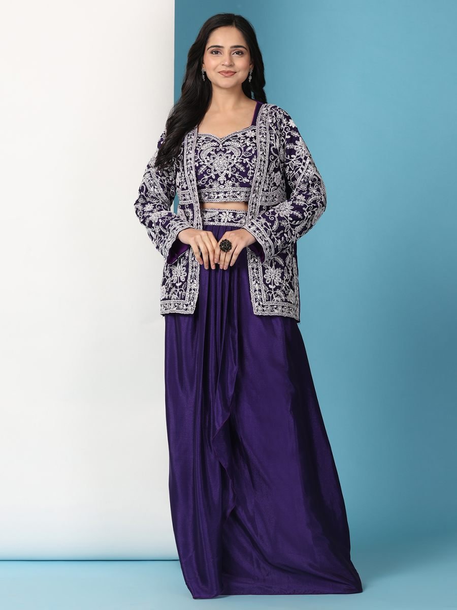 Woman wearing a traditional outfit with a patterned top and purple skirt against a blue background