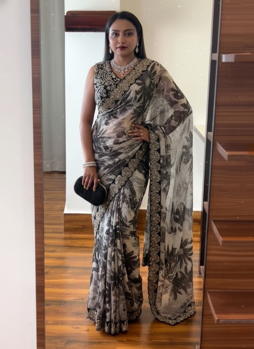 Woman in a patterned saree standing in front of a mirror.
